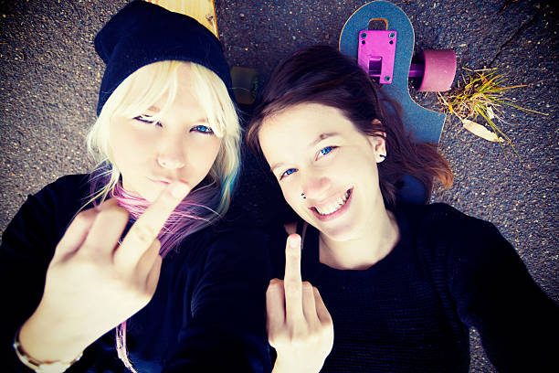 istock Two cheeky girlfriends make middle-finger gestures taking Selfie 510442489