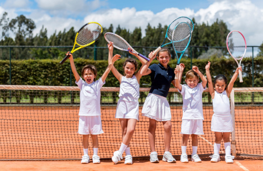 Happy group of kids playing tennis