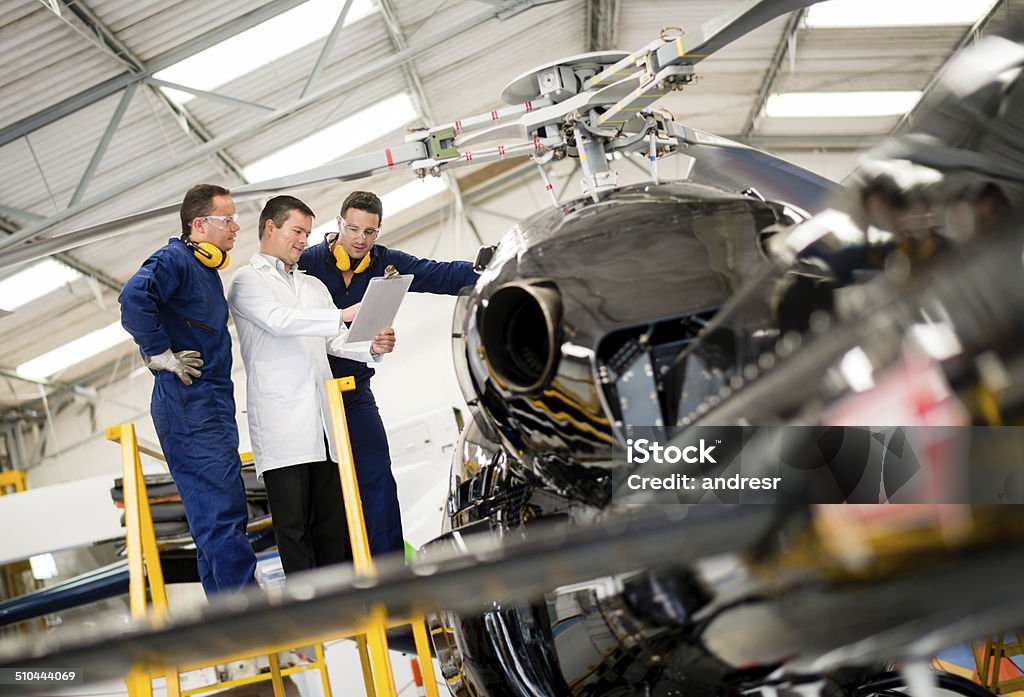 Mechanics fixing a helicopter Mechanics fixing a helicopter at the hangar Helicopter Stock Photo