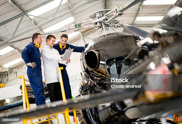 Mechanics Fixing A Helicopter Stock Photo - Download Image Now - Helicopter, Air Vehicle, Repairing
