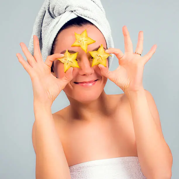 Young woman has carambola slices for her beauty treatment.