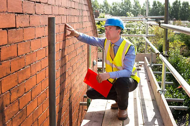 Photo of builder assesses brickwork on a gable end