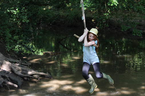 Image of girl on rope swing, swinging across river water