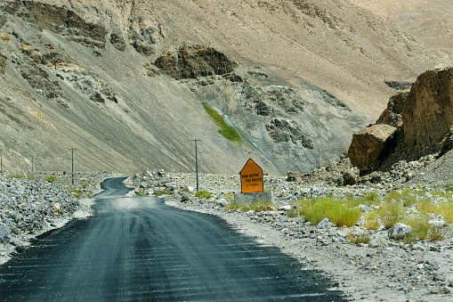 A concrete road towards beautiful rocky mountains and of Himalaya, Road sign, Leh, Ladakh, Jammu and Kashmir, India
