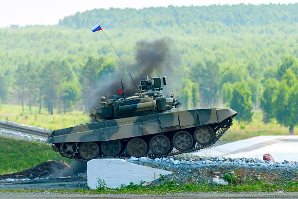 Tank T-80 overcomes a high concrete obstacle stock photo
