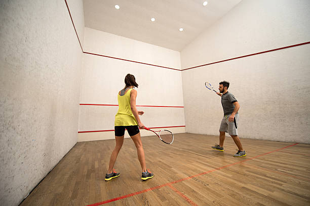 Young friends exercising squash on a court. Athletic couple playing racketball on a court. squash sport stock pictures, royalty-free photos & images
