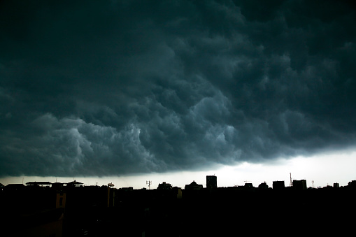 Dark, threatening storm clouds roll over city rooftops in Hanoi, Vietnam.  Horizontal, copy space