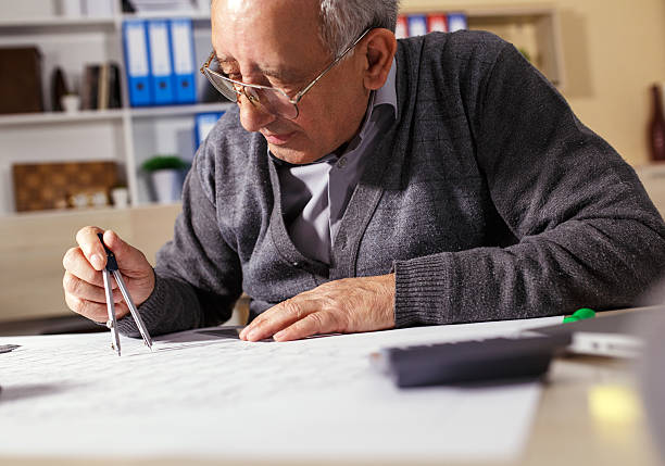 istock Senior architect working on construction blueprint in office 510476476