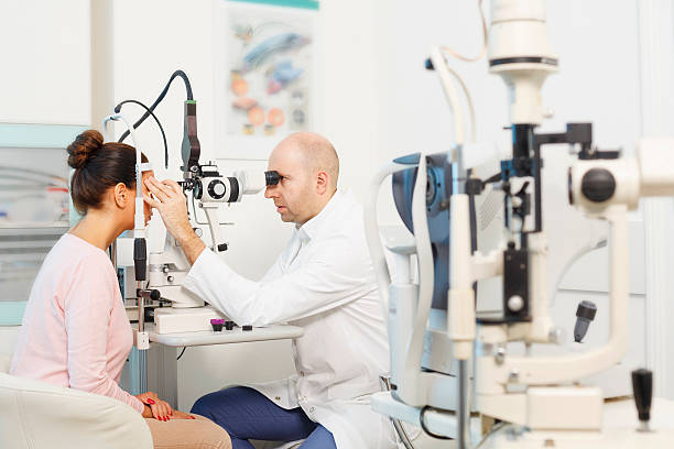 At the optician   Ophthalmology   Doctor ophthalmologist   Optometrist medical eye examination Ophthalmology - ophthalmic clinic. Doctor ophthalmologist  optometrist,  medical eye examination.  Young women, patient  having a checkup, eye examined by specialist.  Very shallow depth of field for soft background. Professional make-up, hairstyle and retouch. Shot with Canon 5DMarkIII, developed from RAW, Adobe RGB color profile. eye test equipment stock pictures, royalty-free photos & images