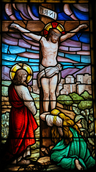 Stained glass window depicting the Crucifixion in the church of San Andres de Texeido, a famous Galician pilgrimage place in the Rias Altas region. This window was created more than 120 years ago, no property release is required.