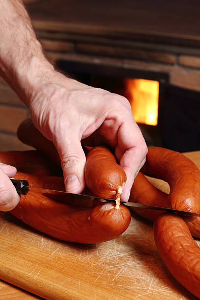 istock Chef cutting sausages at wood fired oven background 510491126