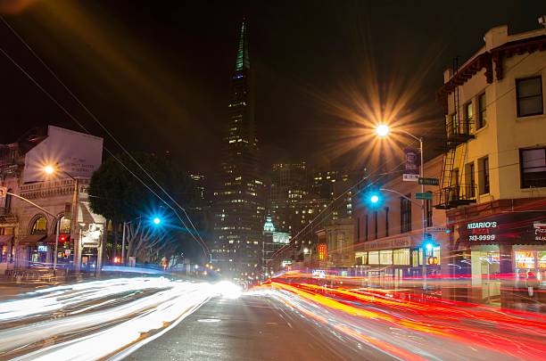 North Beach, San Francisco San Francisco, California, United States of America - March 2, 2014: A night view of Little Italy at the intersection of Columbus and Broadway in North Beach, San Francisco, California, United States of America. View of Transamerica pyramid, italian restaurants, city and car light trails. banksy stock pictures, royalty-free photos & images