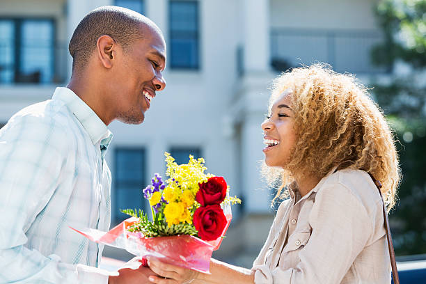 jeune homme donne des fleurs à petite amie - anniversary couple rose black photos et images de collection