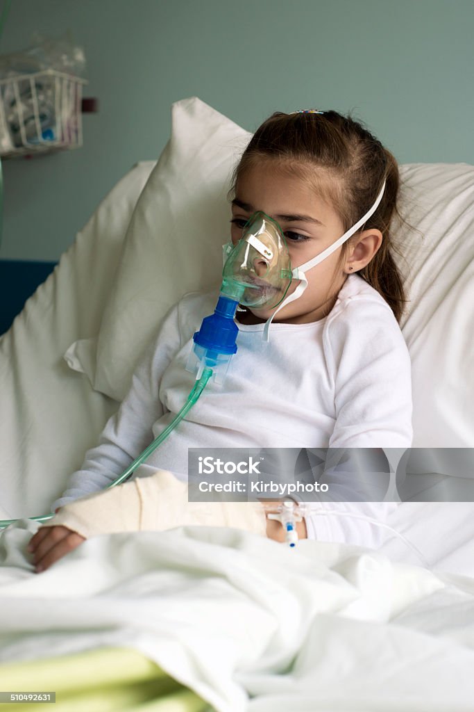 Little patient using a nebuliser Young little girl in the hospital bed using nebuliser to relieve the cough. Vertical framing, shallow depth of field, adobeRGB photo. Hospital Stock Photo