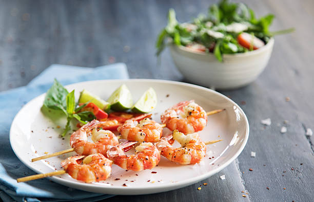 Grilled shrimps Grilled shrimps on skews with lime slices and salad black tiger shrimp stock pictures, royalty-free photos & images