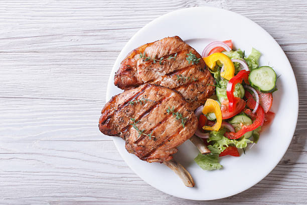 la viande de porc grillés avec une salade de légumes frais sur le dessus - pork tenderloin dinner barbecue photos et images de collection