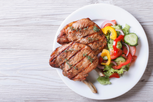 Pork meat grilled with fresh vegetable salad on a white plate. a top view of a horizontal