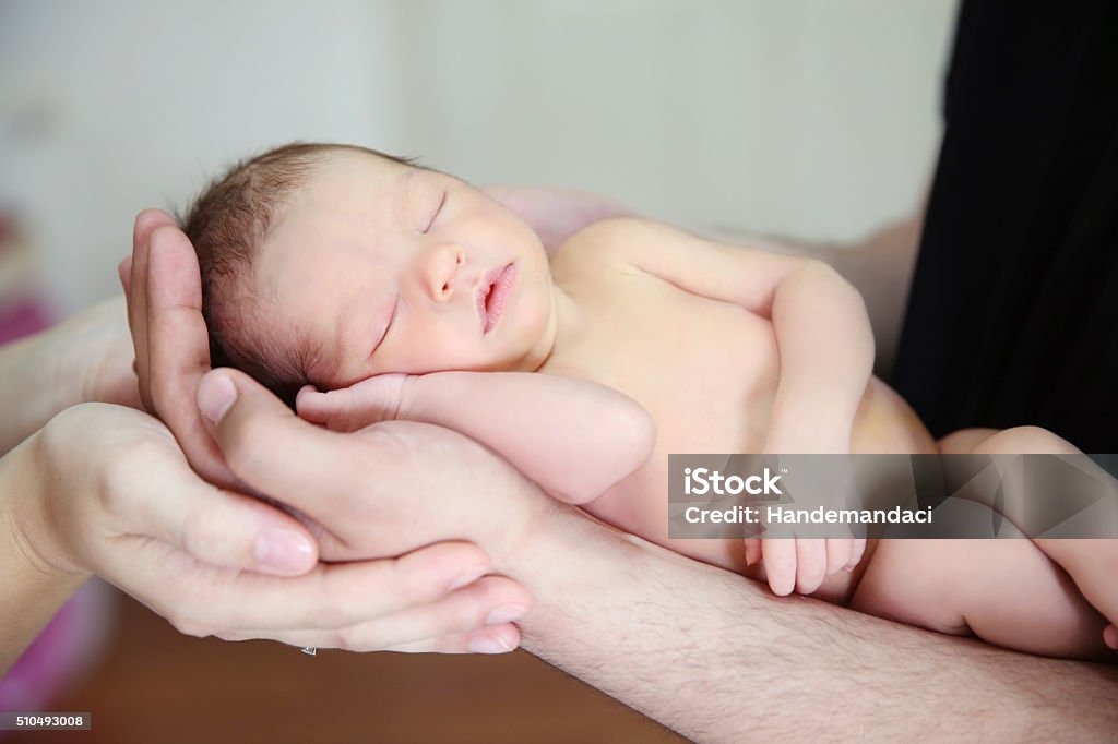 Hands of Father and Mother Holding Newborn Baby  Stock Image Color photo of the hands of a new father and mother holding their newborn baby. Baby - Human Age Stock Photo