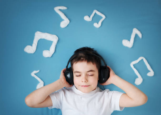 happy seven years old boy on blue blanket background with headphones and musical notes on blue background
