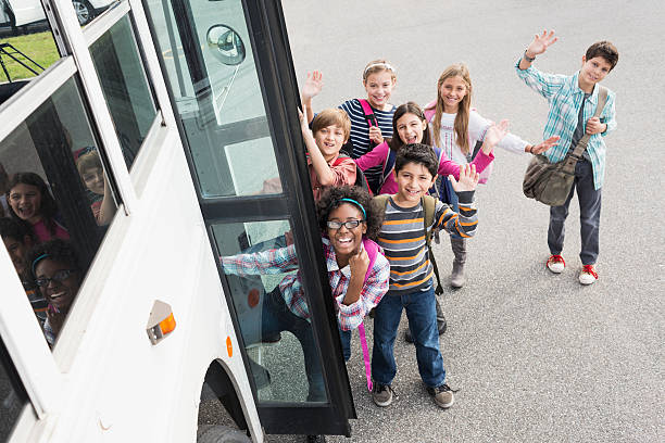 Children getting on school bus Group of multi-ethnic elementary school children (10-12 years) getting on school bus. junior high photos stock pictures, royalty-free photos & images