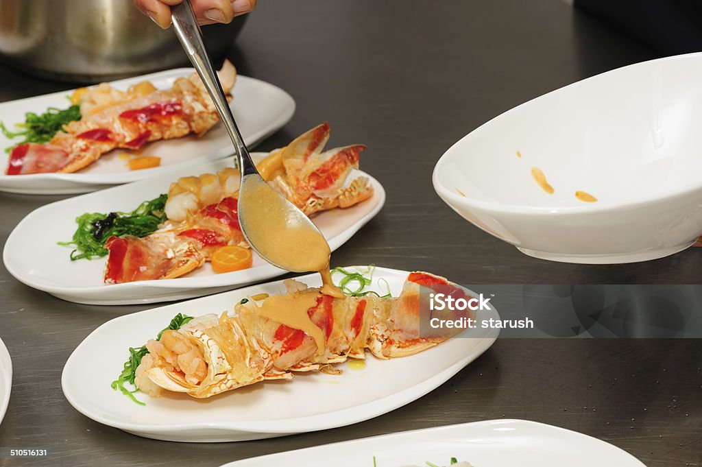 Decorating cooked lobster on plate Decorating of prepared lobsters on plates, pouring the sauce Activity Stock Photo