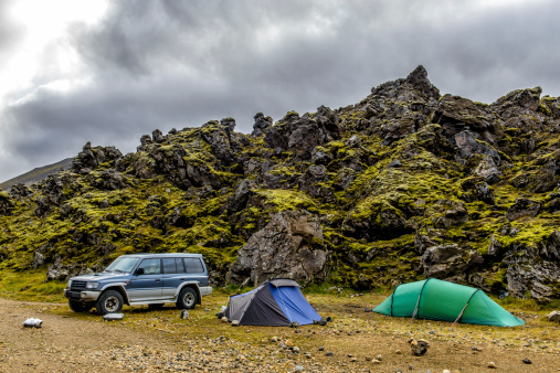 Two tents and a 4x4 off road vehicle next to a lava field in the Landmannalaugar area in Iceland.