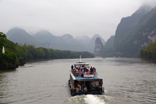 Guilin, China - April 25, 2014: tourists crowd on a boat admire the beautiful Li river's karst scenery. It ranges 83 kilometers from Guilin to Yangshuo, where the Karst mountain and river sights highlight the famous Li River cruise.