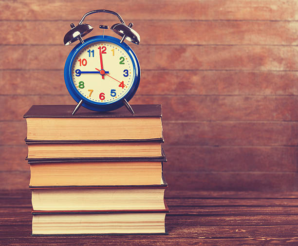 istock Alarm clock and books on wooden table. 510539063