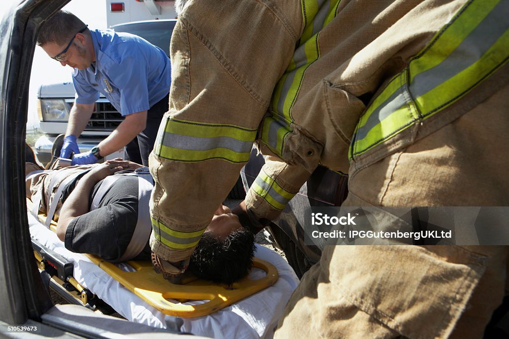 Firefighter and paramedics taking victim out of crashed car Paramedic Stock Photo