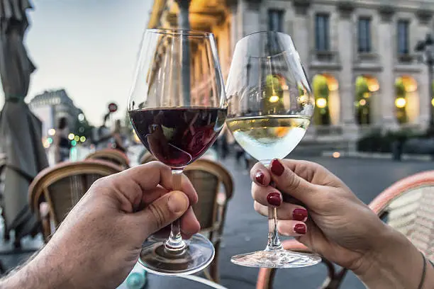 Unrecognizable Couple raising glasses with red and white wine in Bordeaux - France