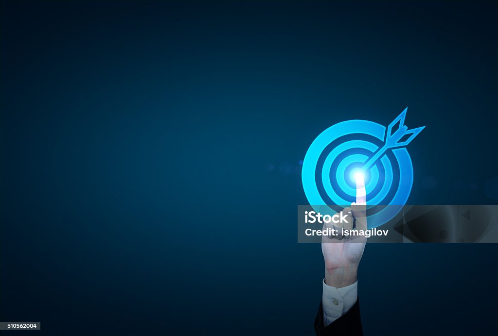 Reaching an aim A hand in a suit touching the center of a picture of a target which gets blue. Dark blue background. Concept of achieving a goal. Solution Stock Photo