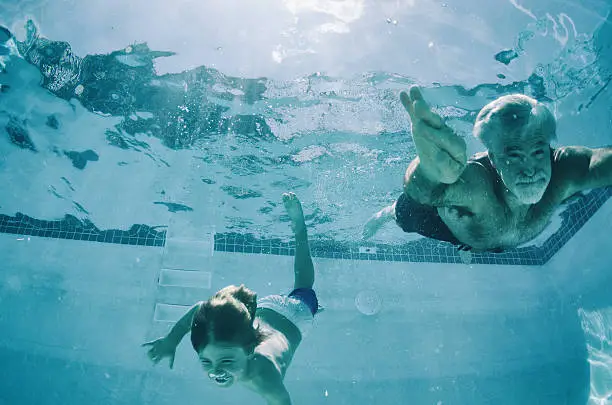 Grandpa and Grandson swimming underwater in summer