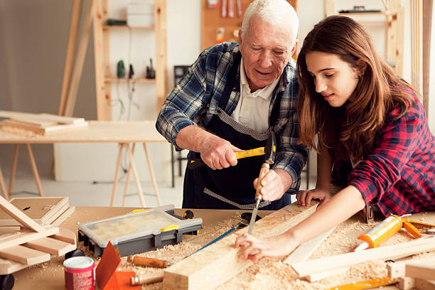 Girl with grandpa at workshop Grandpa with granddaughter enjoy  at grandpa's carpentry workshop old building stock pictures, royalty-free photos & images