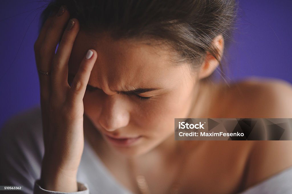 Teen woman with headache holding her hand to head Teen woman with headache holding her hand to the head Headache Stock Photo