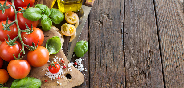 Cherry tomatoes, basil and olive oil on a wooden table