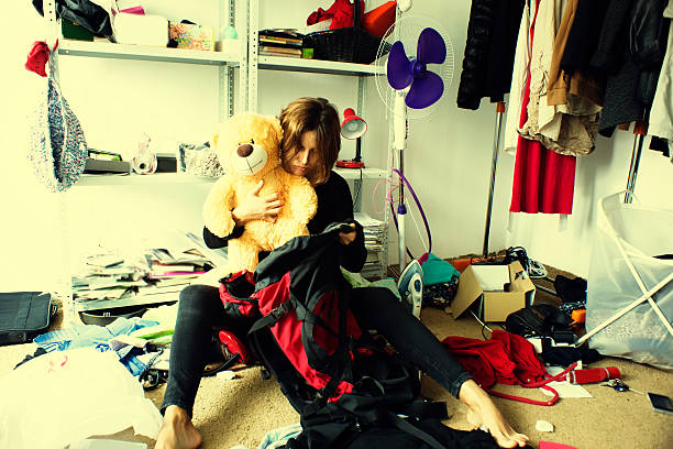 woman is packing backpack in a messy room stock photo