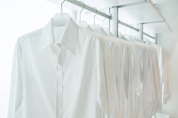 white shirts hanging on built-in cloths racks stock photo