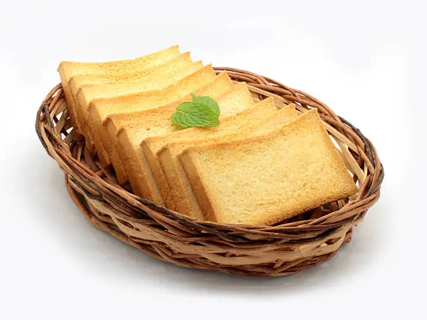 Rusks aligned in a bamboo basket, topped with a mint leaf