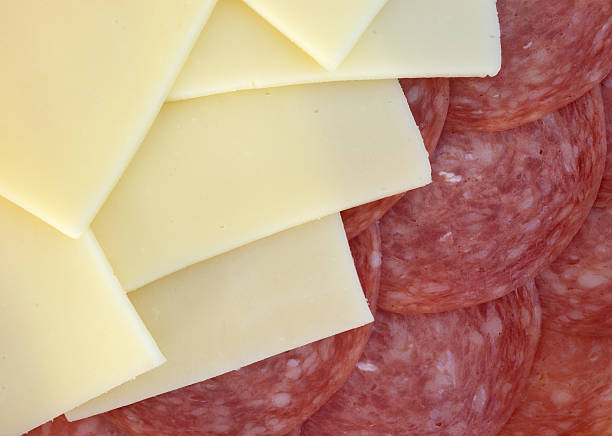 A close view of slices of provolone cheese and genoa salami illuminated with natural light.