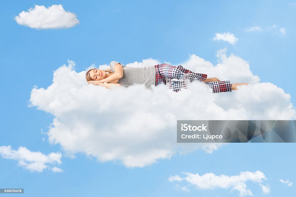 Tranquil scene of a woman sleeping on cloud Tranquil scene of a young woman dreaming and sleeping on a cloud up in the sky Sleeping Stock Photo
