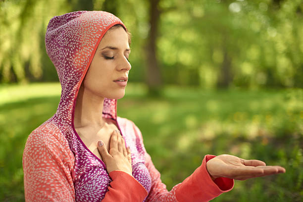 friedliche und ruhige frau üben hübsche bewusstsein achtsamkeit von meditieren - spirituality hand on heart meditating women stock-fotos und bilder