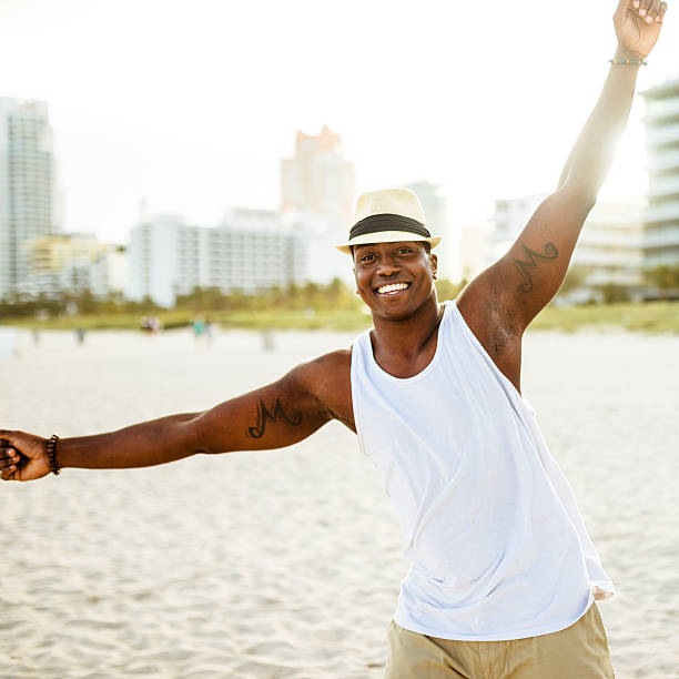 afrikanische mann tanzen am strand von miami - men latin american and hispanic ethnicity young men smiling stock-fotos und bilder