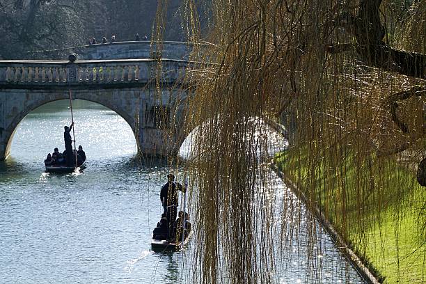 Shallow focus on the foreground punts throws the background Cambridge university buildings and students out of focus in this tranquil English scene.