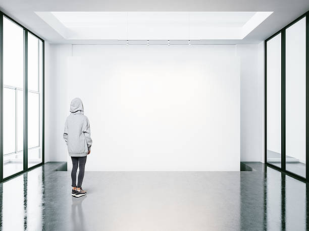 istock Young woman in empty modern gallery looking at the blank 510584606