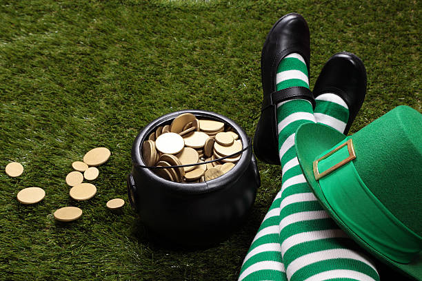 Female Leprechaun on the grass next to a pot of gold.