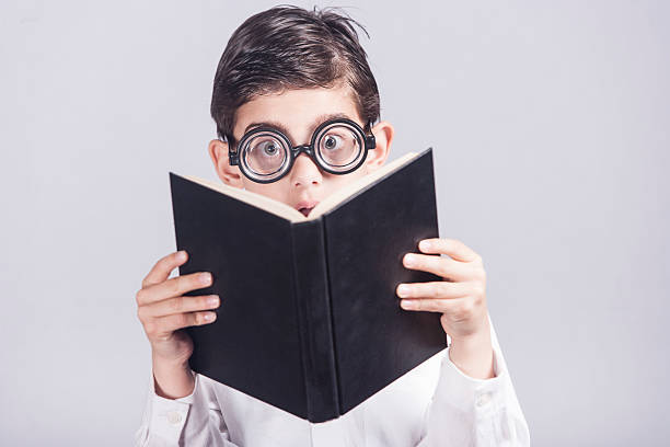 istock Funny nerdy little boy reading a book 510587318