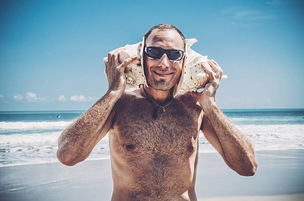 istock Smiling Man listening to Sea Shells 510588004