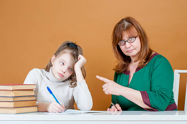 Strict woman teacher points at student. stock photo