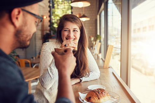 Portrait of a casual young couple having coffee together at the coffee shop. Young man and woman meeting at cafe.