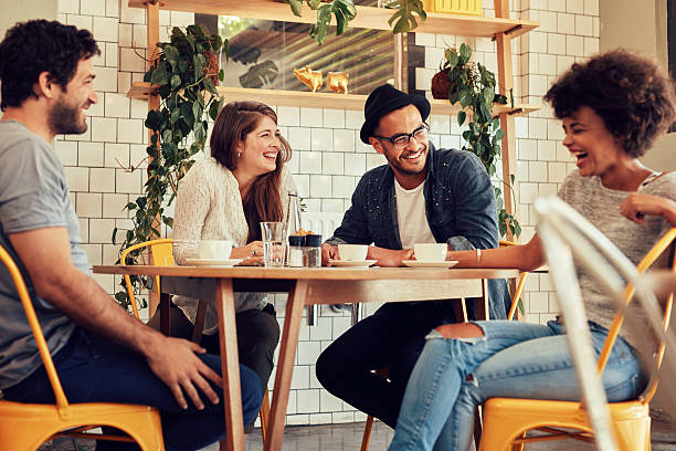 Friends having a great time in cafe Young people having a great time in cafe. Friends smiling and sitting in a coffee shop, drinking coffee and enjoying together. small group of people stock pictures, royalty-free photos & images